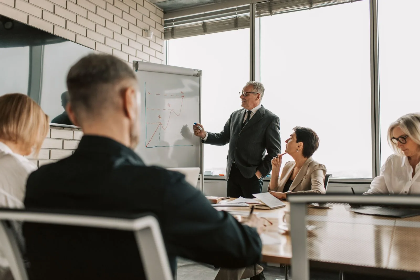 Business team collaborating at a growth-strategy meeting, upward trend sketched on the flip chart in the background