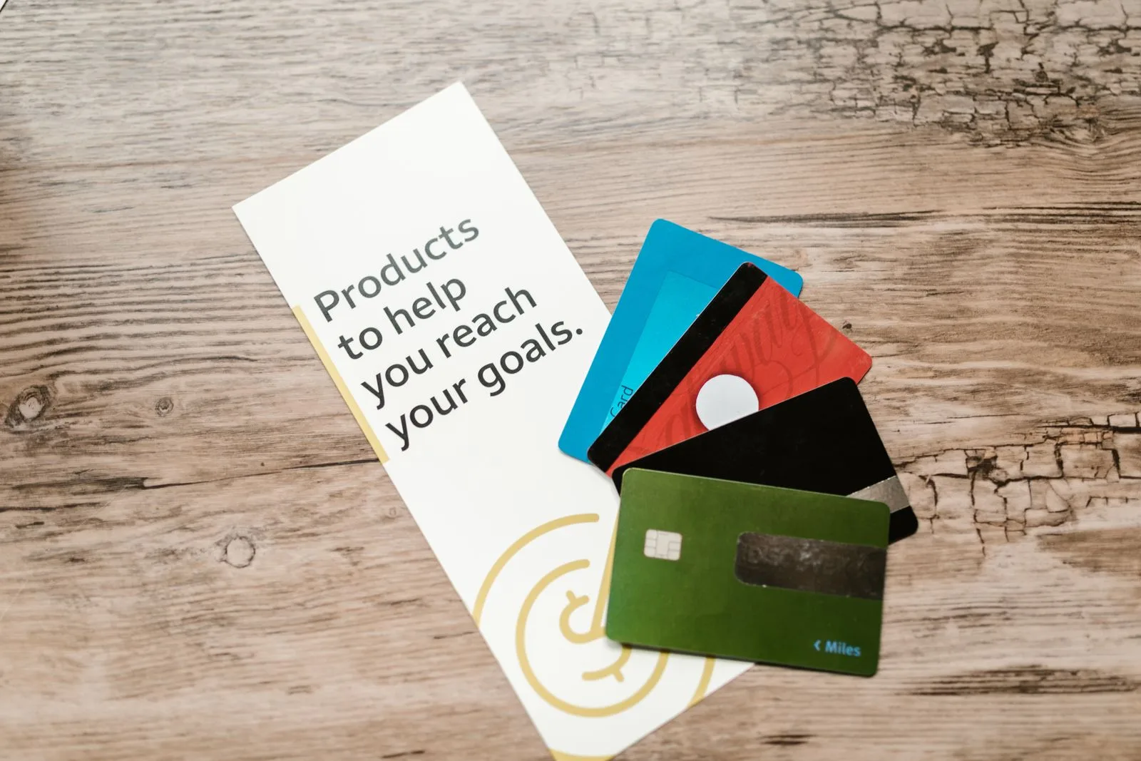 Four business credit cards fanned across a wooden desk next to a card that reads Products to help you reach your goals