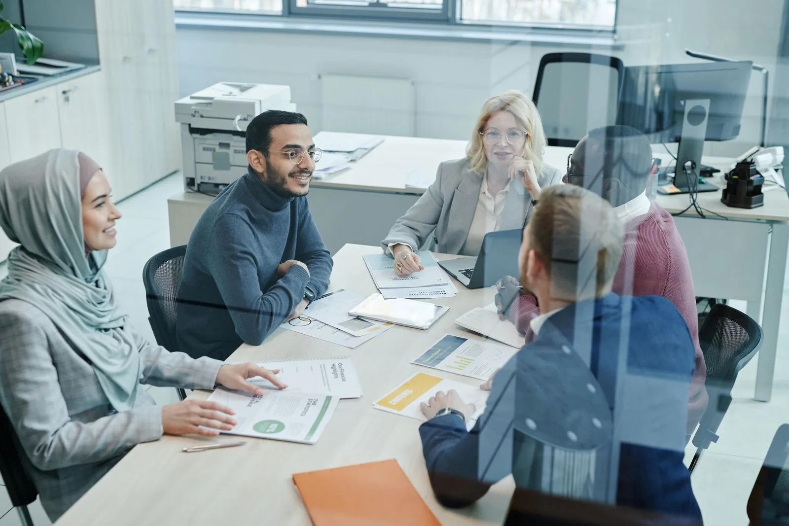 Diverse team of professionals gathered around a table in a bright modern office collaborating on planning documents