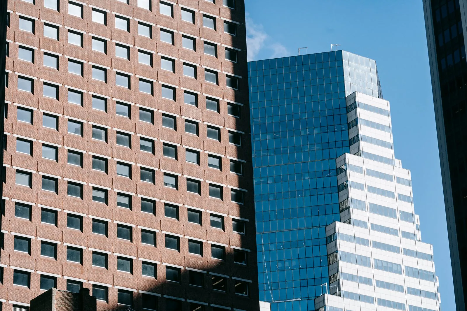 Modern commercial office buildings in an urban skyline, brick tower next to a glass tower under blue sky