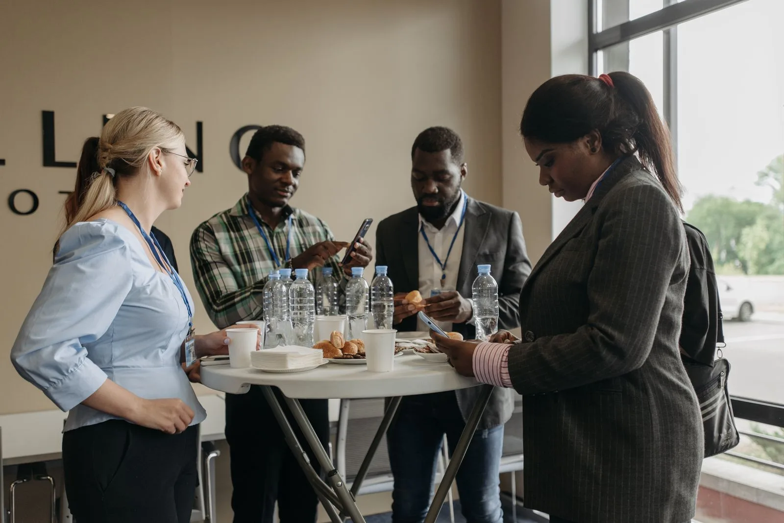 Four business professionals with lanyards networking around a small standing table at a corporate event