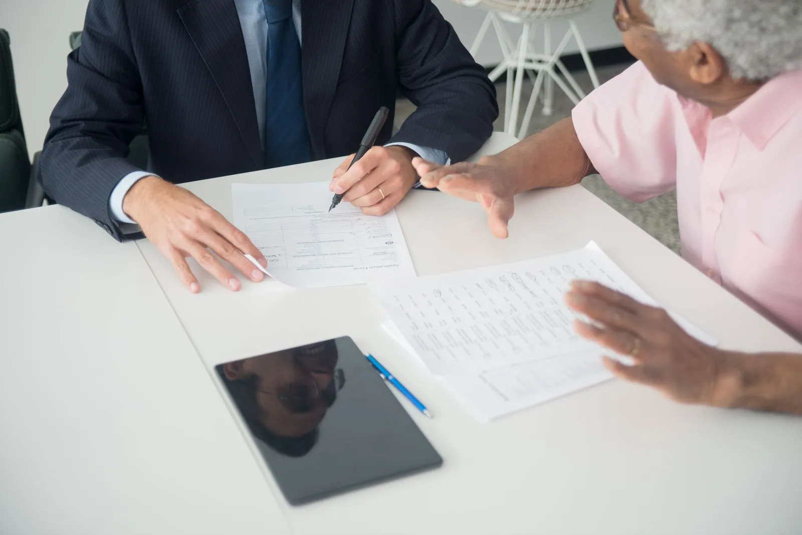 Business advisor and client reviewing a printed application form together at a bright desk